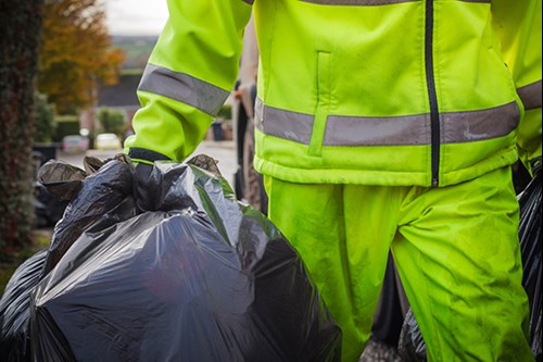 Refuse loader carrying black sacks