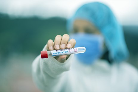 Stock image health professional holding a COVID-19 test tube sample by Fernando Zhiminaicela from Pixabay