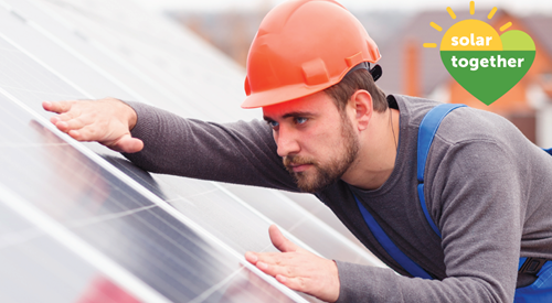 man wearing hard hat fixing solar panels to a roof