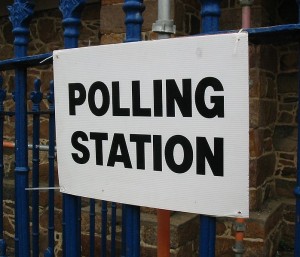 polling station sign tied to blue railings 