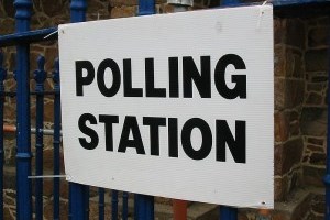 polling station sign tied to blue railings 