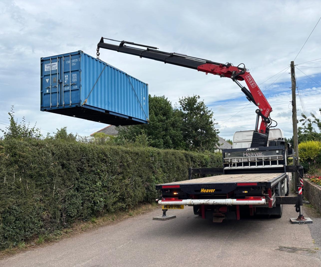 image of a blue container being lifted by an orange crane arm 