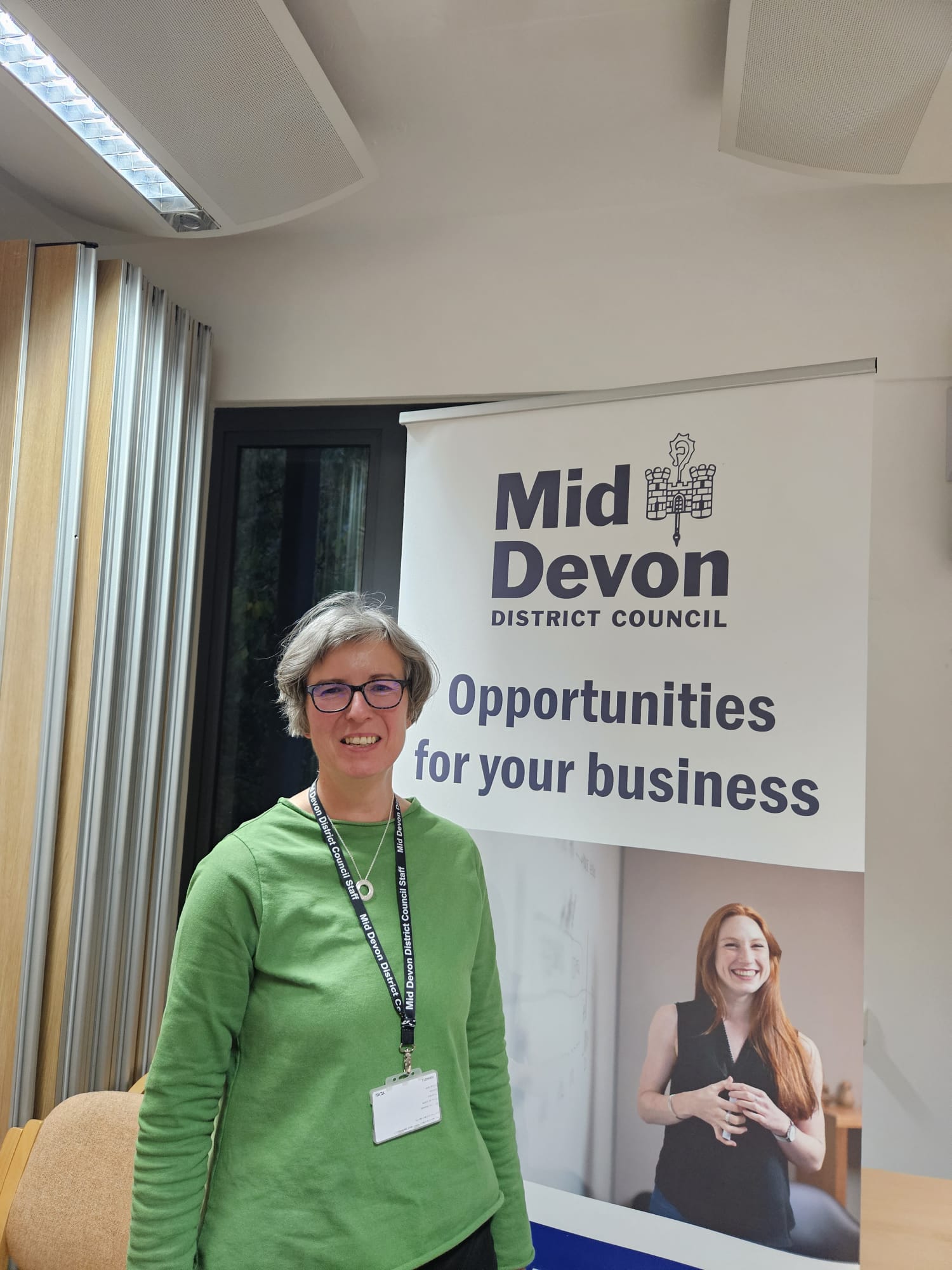 Linda Perry wearing green jumper in front of white banner 