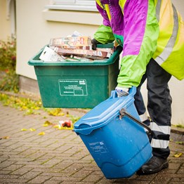 blue food caddy and green recycling box being carried